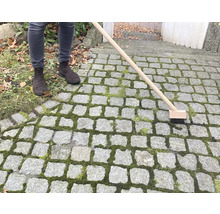 Personne nettoyant le pavé en pierre avec une brosse à joints