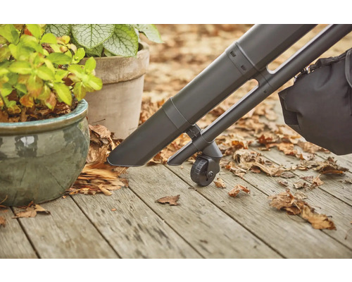Aspirateur de feuilles en utilisation sur une terrasse en bois à côté de pots plantés.