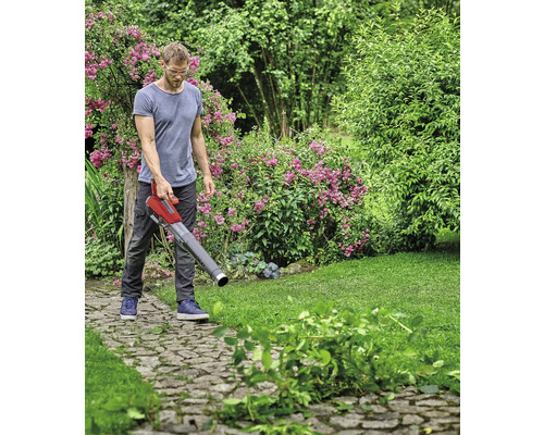 Ein Mann benutzt einen Laubsauger im Garten, um Blätter und Gartenabfälle zu entfernen.