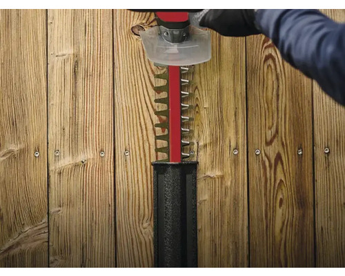 Heckenschere im Einsatz vor Holzwand