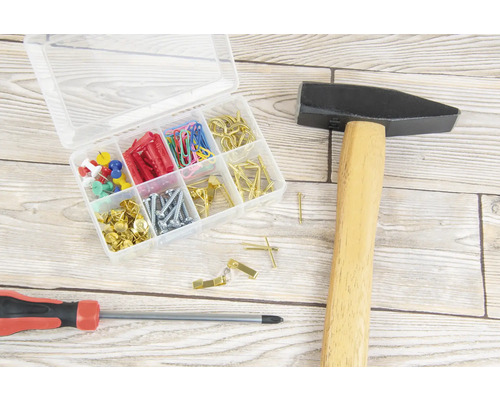 Marteau, tournevis et boîte d''assortiment avec vis, chevilles, clous, punaises et trombones sur une surface en bois