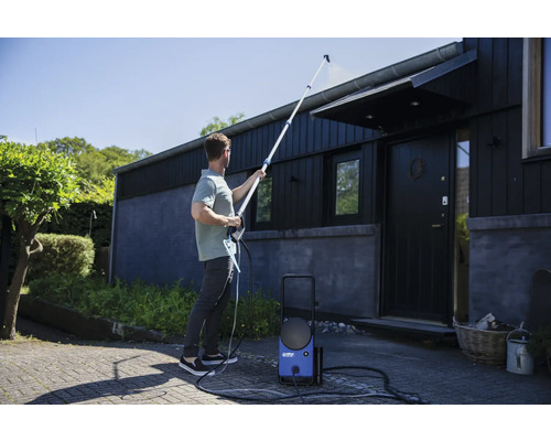 Homme nettoie le toit d''une maison avec un nettoyeur haute pression