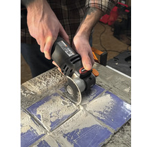 Une personne utilise un outil multifonction pour couper des carreaux.