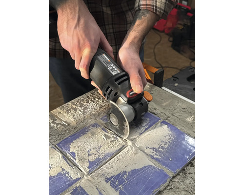 Une personne utilise un outil multifonction pour couper des carreaux.