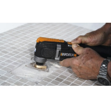 Vue détaillée d''une personne travaillant des carreaux avec un outil multifonction, marque Worx