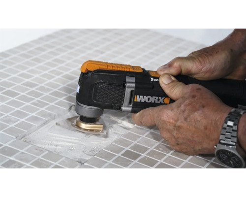 Vue détaillée d''une personne travaillant des carreaux avec un outil multifonction, marque Worx