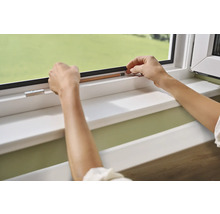 Des mains fixent un joint d''étanchéité sur un cadre de fenêtre