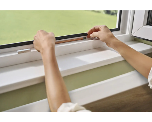 Des mains fixent un joint d''étanchéité sur un cadre de fenêtre