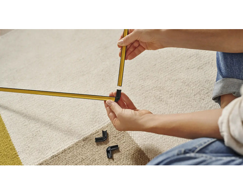 Une personne assemble une moulure décorative de couleur or avec des raccords d''angle.