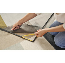 Personne fixant une moustiquaire avec un outil sur le cadre de la fenêtre