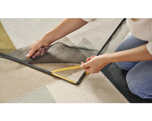 Personne fixant une moustiquaire avec un outil sur le cadre de la fenêtre