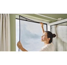 Femme installant une moustiquaire sur une fenêtre