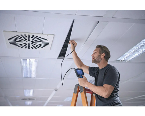 Un homme effectue une inspection du plafond à l''aide d''un endoscope sur une échelle