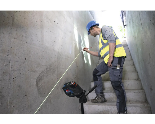 Un ouvrier du bâtiment utilise un laser linéaire pour l''alignement sur un mur en béton.