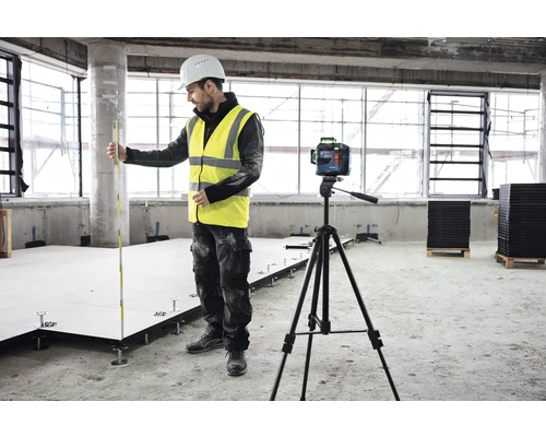 Baustelle mit Arbeiter, Nivelliergerät auf Stativ und Doppelbodenplatten