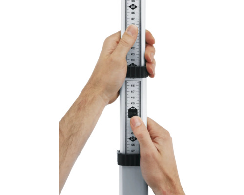 Une mire de nivellement est tenue par deux mains pour effectuer une mesure de hauteur.