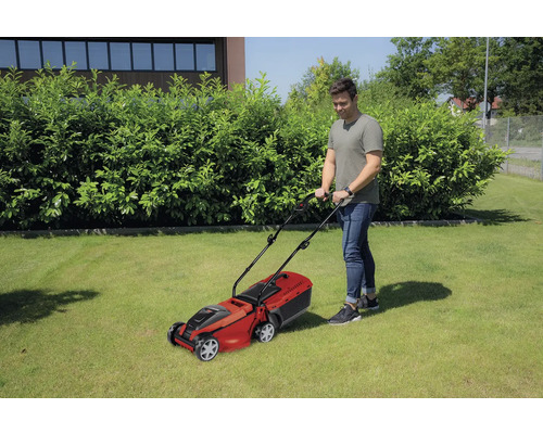 Mann mäht Rasen mit einem Rasenmäher im Garten.