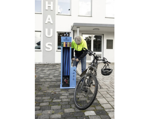 Mann pumpt Fahrradreifen an einer BikeBroz Fahrradreparaturstation vor einem Gebäude