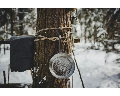 Metallpfanne, die mit Seil an einem Baum befestigt ist, im winterlichen Wald.
