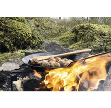 Fleischbällchen in einer Pfanne über einem Lagerfeuer mit Holzlöffel