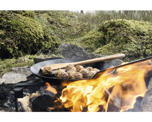 Fleischbällchen in einer Pfanne über einem Lagerfeuer mit Holzlöffel