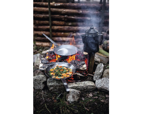 Préparation de plats en extérieur avec deux poêles à frire et une cafetière au-dessus d''un feu ouvert.