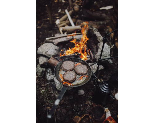 Poêle à frire avec des galettes de hamburger sur un feu de camp