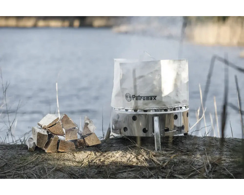 Pot à feu Petromax avec pile de bois au bord du lac