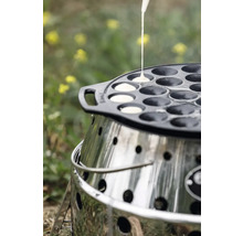 Poffertjes-Pfanne aus Gusseisen auf einem Grill, während Teig in die Mulden gegossen wird