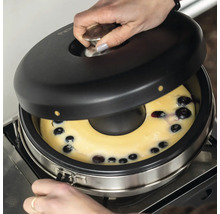 Frau öffnet Backofen mit Blaubeerkuchen