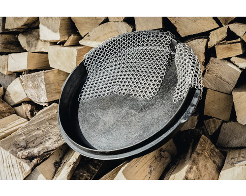 Poêle en fonte avec nettoyeur à chaîne sur une pile de bois