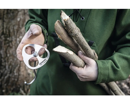 Une personne tient un crochet d''allumage Petromax et des morceaux de bois.