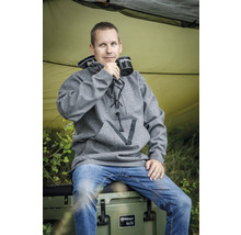 Ein Mann sitzt auf einer Kühlbox und trinkt aus einer Tasse. Er trägt einen grauen Wollpullover.