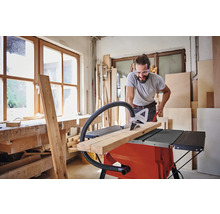 Homme coupant du bois avec une scie circulaire sur table dans un atelier