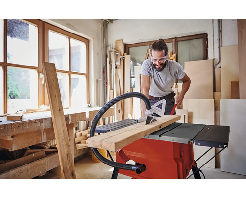 Homme coupant du bois avec une scie circulaire sur table dans un atelier