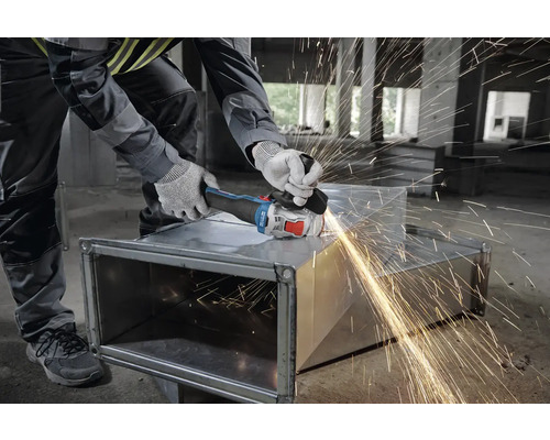 Artisan travaillant le métal avec une meuleuse d'angle, des étincelles jaillissent.