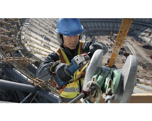 Un ouvrier du bâtiment meule du métal avec une meuleuse d'angle sur un chantier.