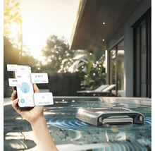 Personne contrôlant un robot de nettoyage de piscine avec un smartphone dans une piscine extérieure