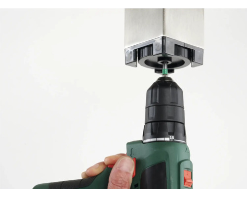 Une perceuse fixe un poteau de clôture.