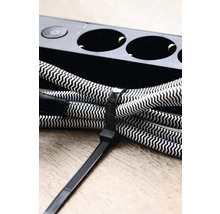 Eine Kabeltrommel mit Textilkabel und Kabelbinder liegt neben einer Steckdosenleiste.