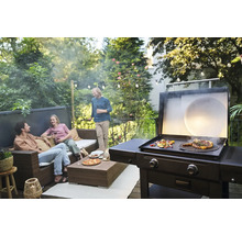 Scène avec un barbecue en train de cuire des aliments et des personnes discutant sur une terrasse.