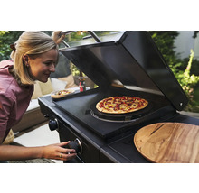 Femme préparant une pizza sur un barbecue à gaz noir.
