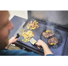 Un homme prépare un steak, des légumes et du riz sur un gril