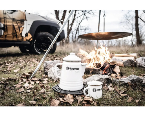 Scène avec cafetière blanche Petromax Perkomax, tasse, feu de camp et voiture en arrière-plan