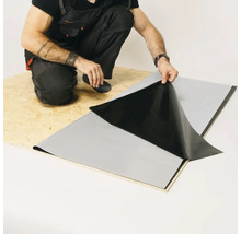 Un artisan pose une membrane d''étanchéité sur une plaque de bois