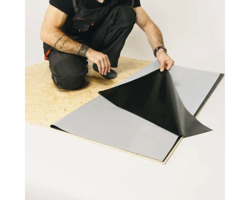 Un artisan pose une membrane d''étanchéité sur une plaque de bois