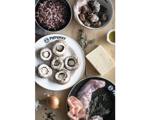 Ingrédients pour une poêlée de champignons avec des lardons, des dattes, du fromage, du gibier, des oignons et des herbes sur une table en bois