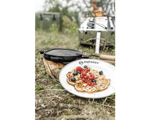 Scène d''extérieur avec des crêpes dans une assiette, une poêle en fonte et un réchaud