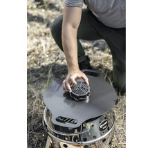 Person hockt und befestigt einen Aufsatz auf einem Petromax Atago Grill.