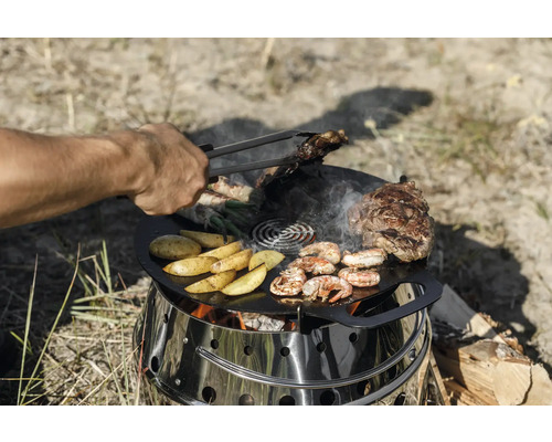Grill mit Grillplatte, darauf Fleisch, Kartoffeln, Garnelen und Gemüse.